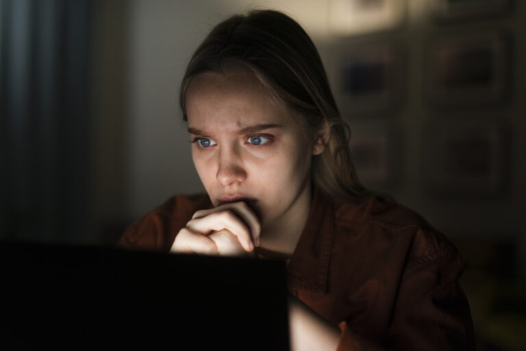 Woman closing laptop in repentance after realizing she has created a false social media persona.